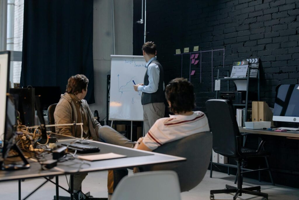 Men Having a Meeting in a Modern Office and Looking at a Whiteboard